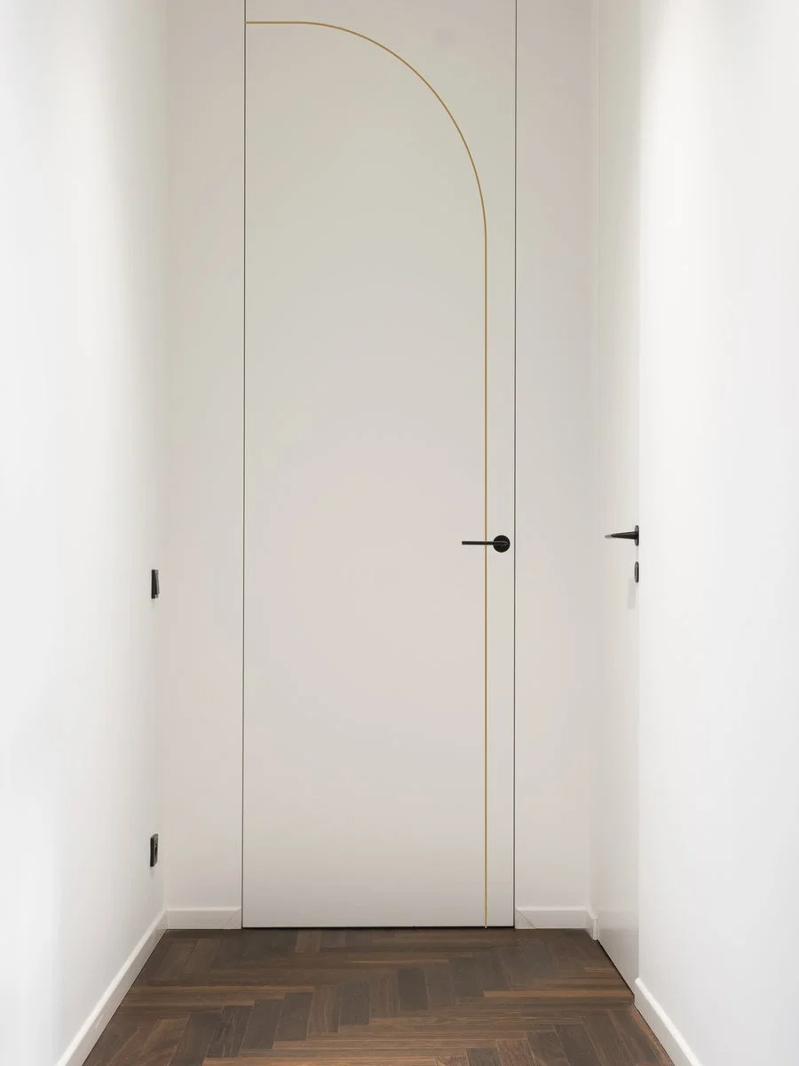 Geometria — a white concealed door in a hallway with a gilded arcing line