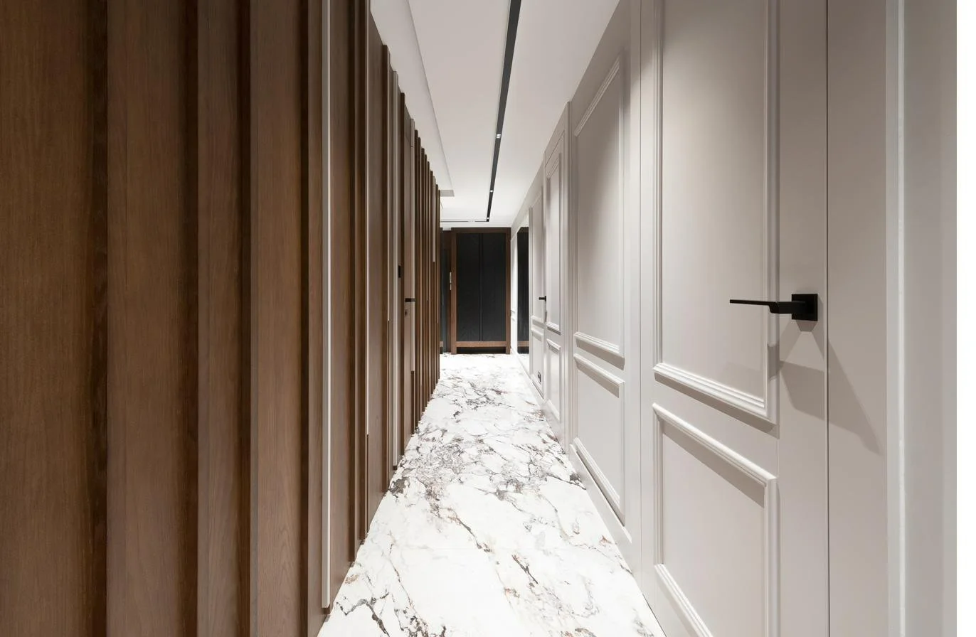 A hallway with two wall systems — dark walnut and a light white