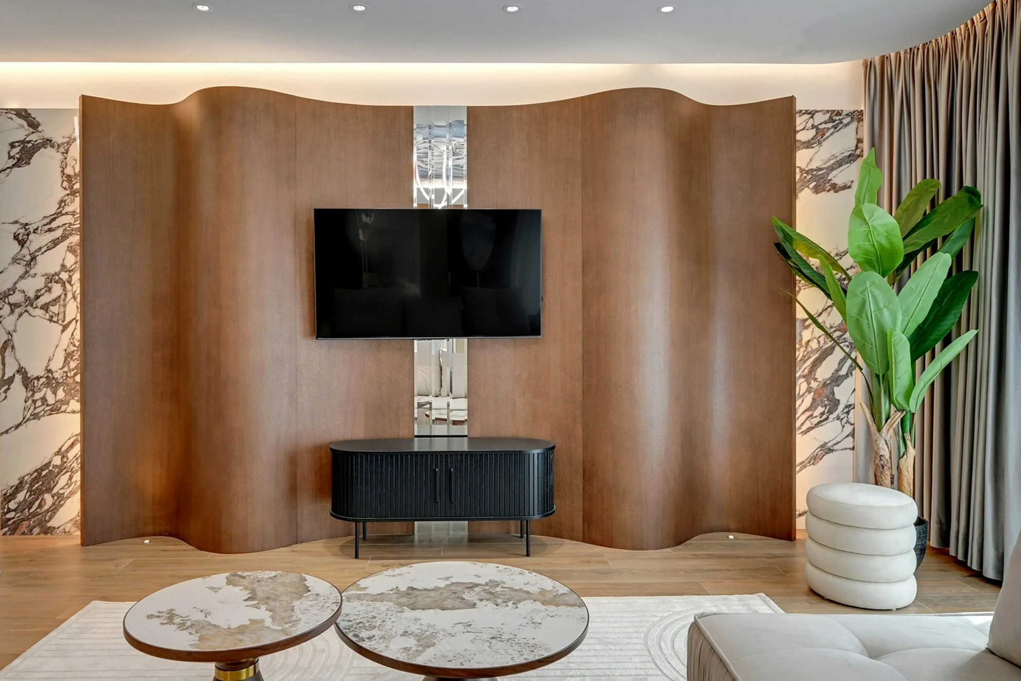 Living room with undulating veneered wall joinery and a black chest beneath the television